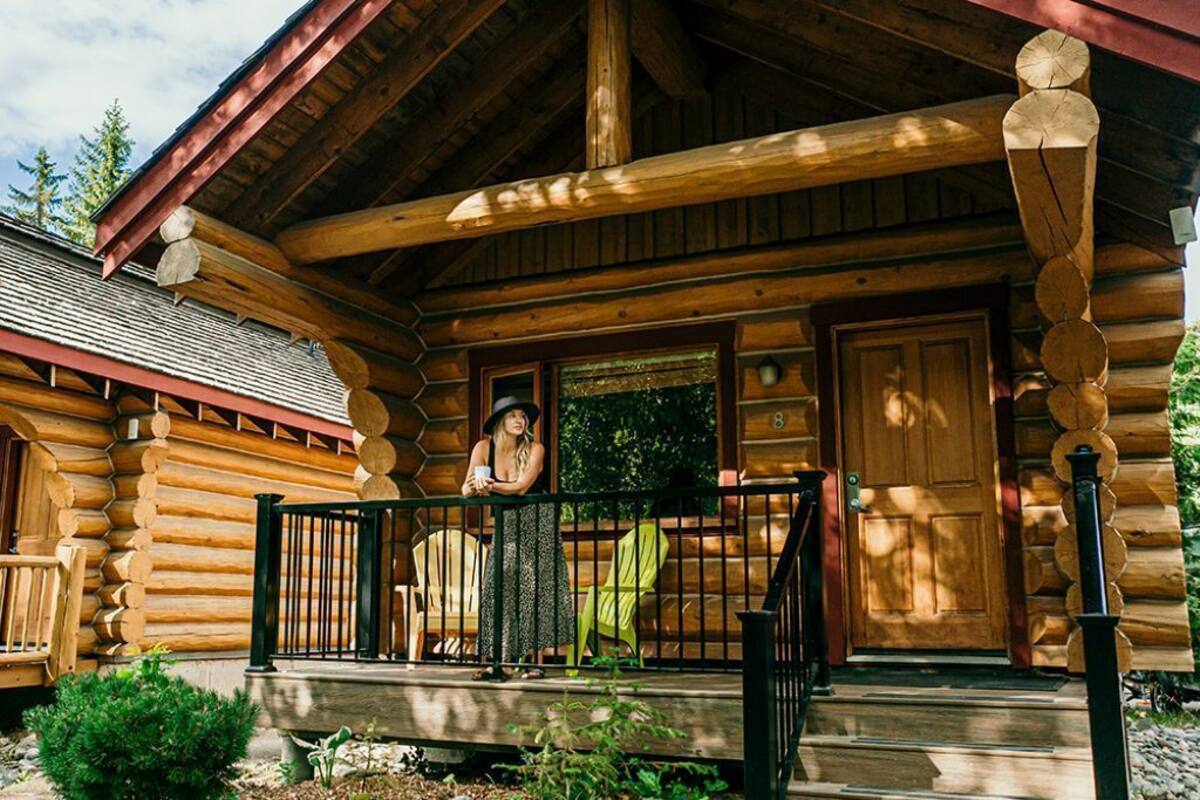 A log cabin with a porch, wooden beams, and a door.