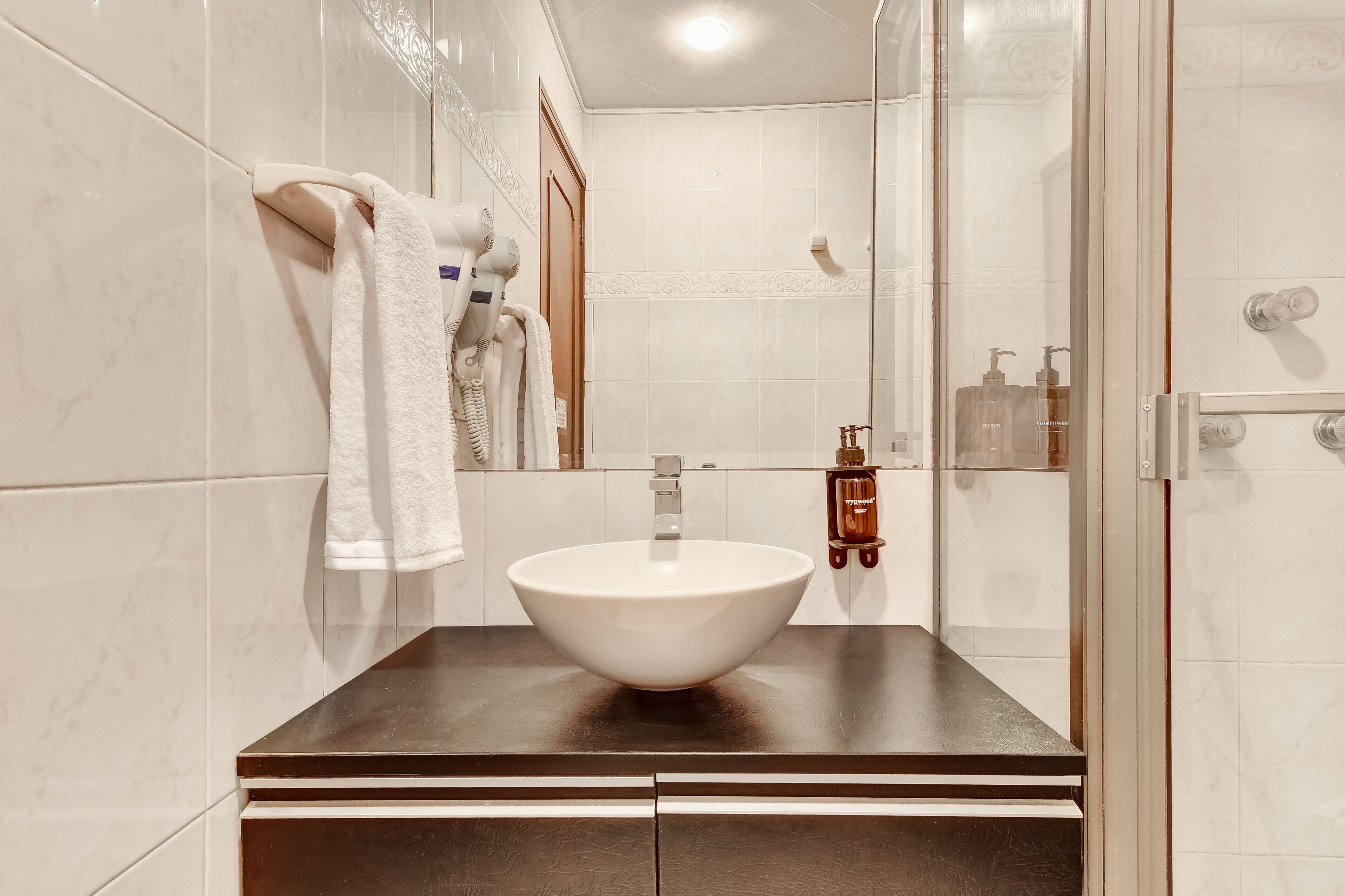 Un baño con lavamanos blanco, toallero y cabina de ducha de vidrio.