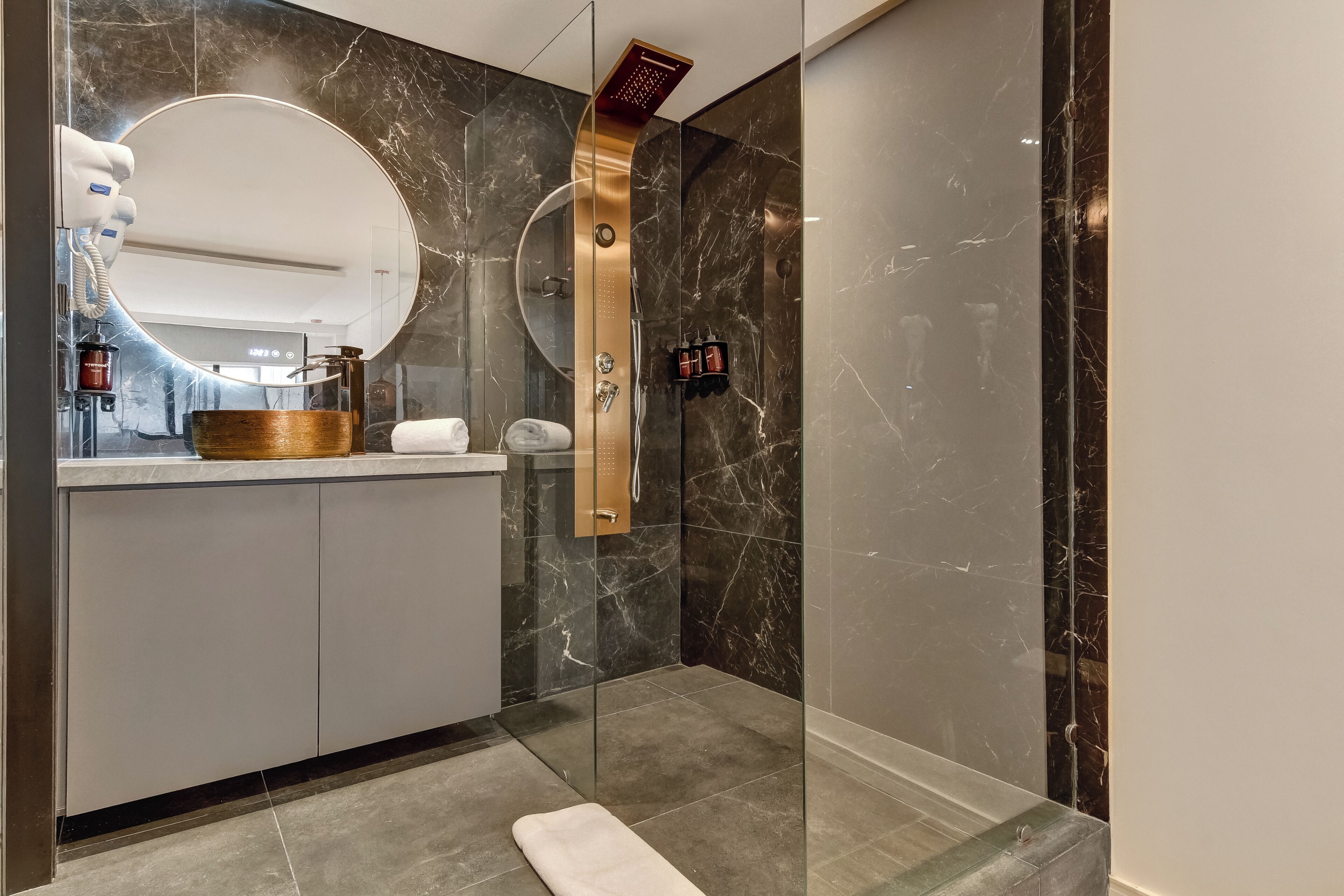 A modern bathroom with a marble vanity, a glass shower enclosure, and a towel rack.