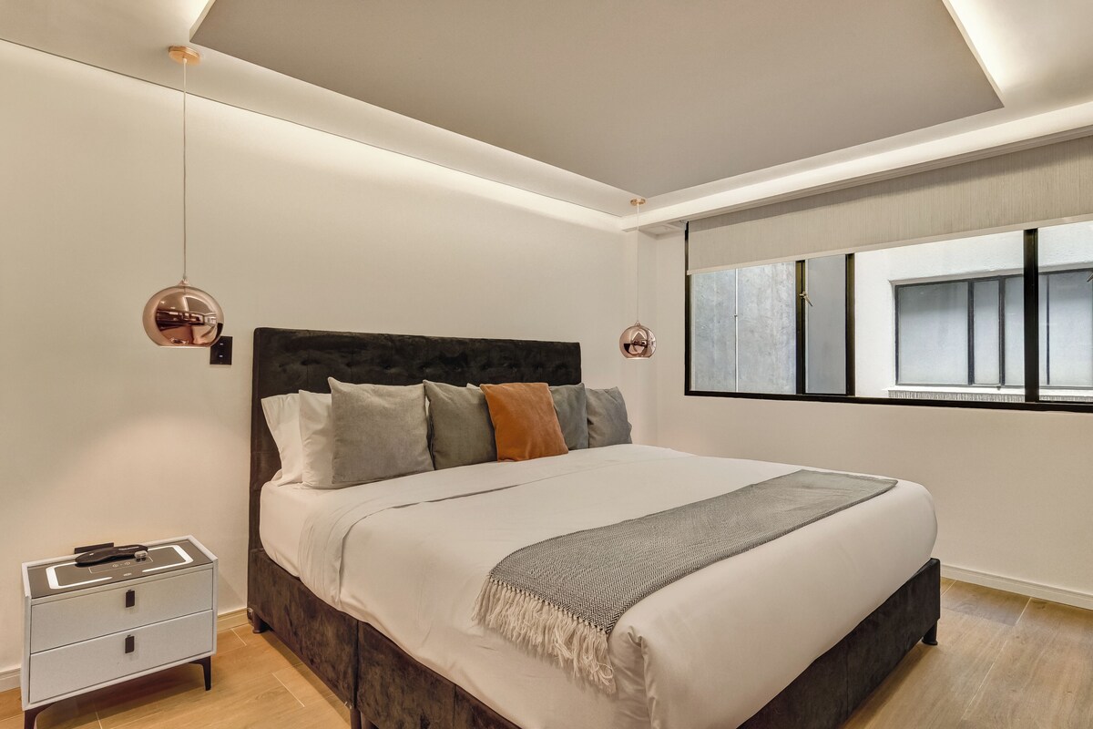 Ein modernes Schlafzimmer mit einem Bett, Nachttischen und einem Fenster mit Jalousien.