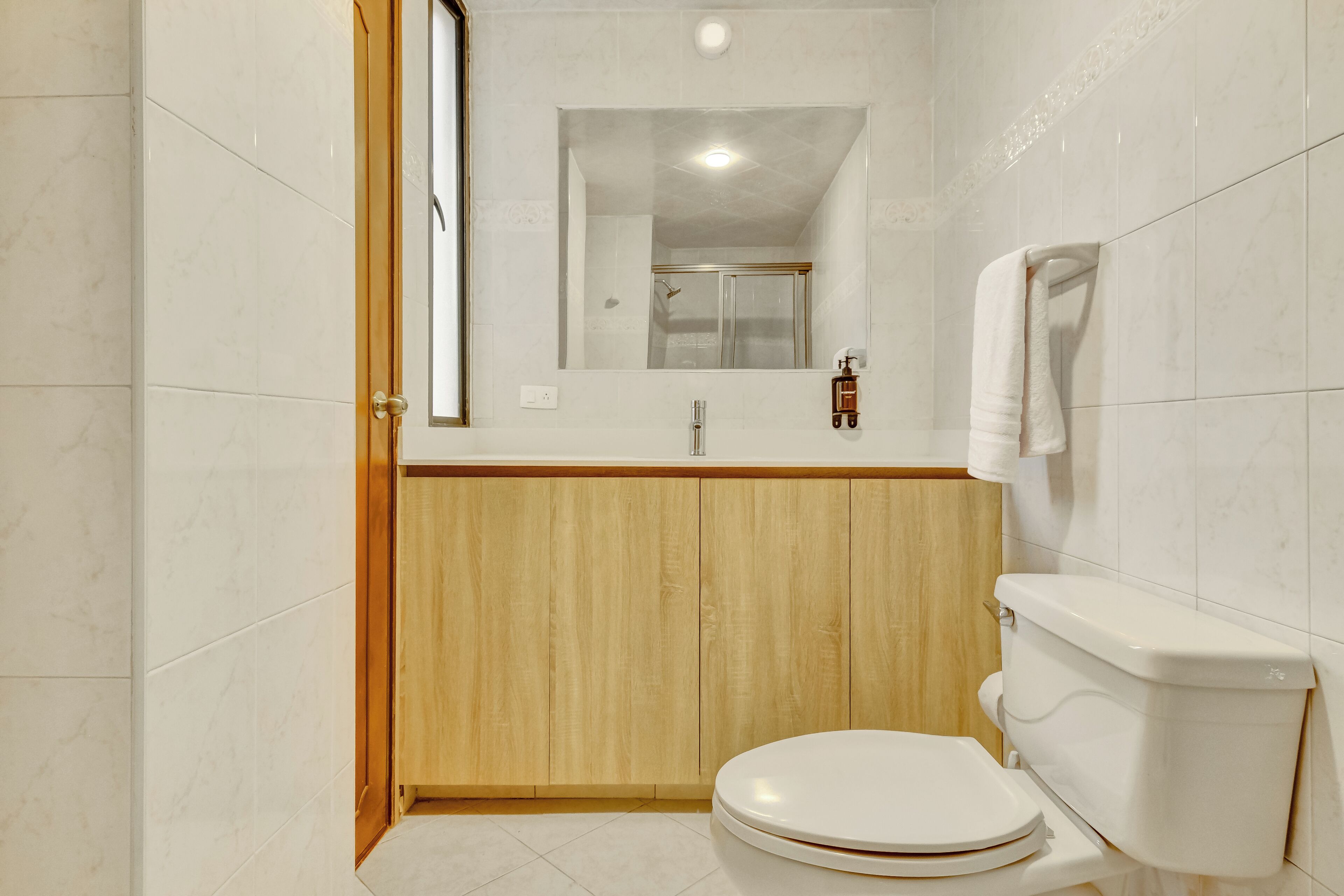Ein Badezimmer mit Toilette, einem Holzkästen, einem Spiegel und einer Dusche.
