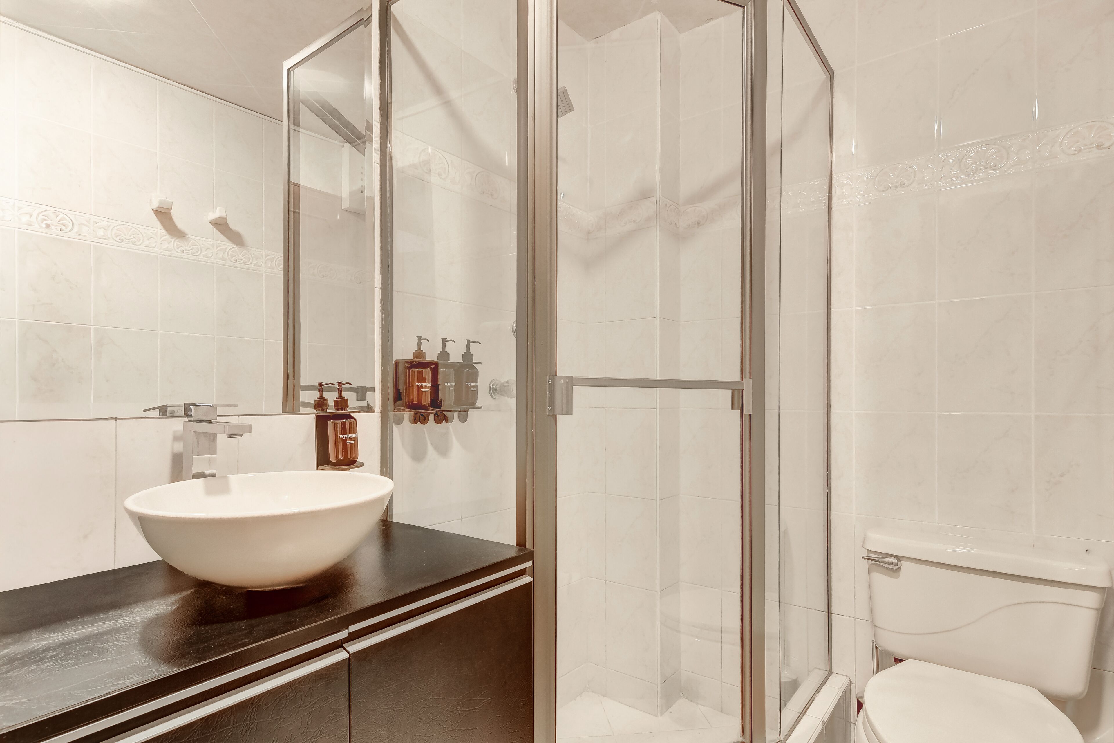 A bathroom with a large vessel sink, a glass-enclosed shower, and a toilet.