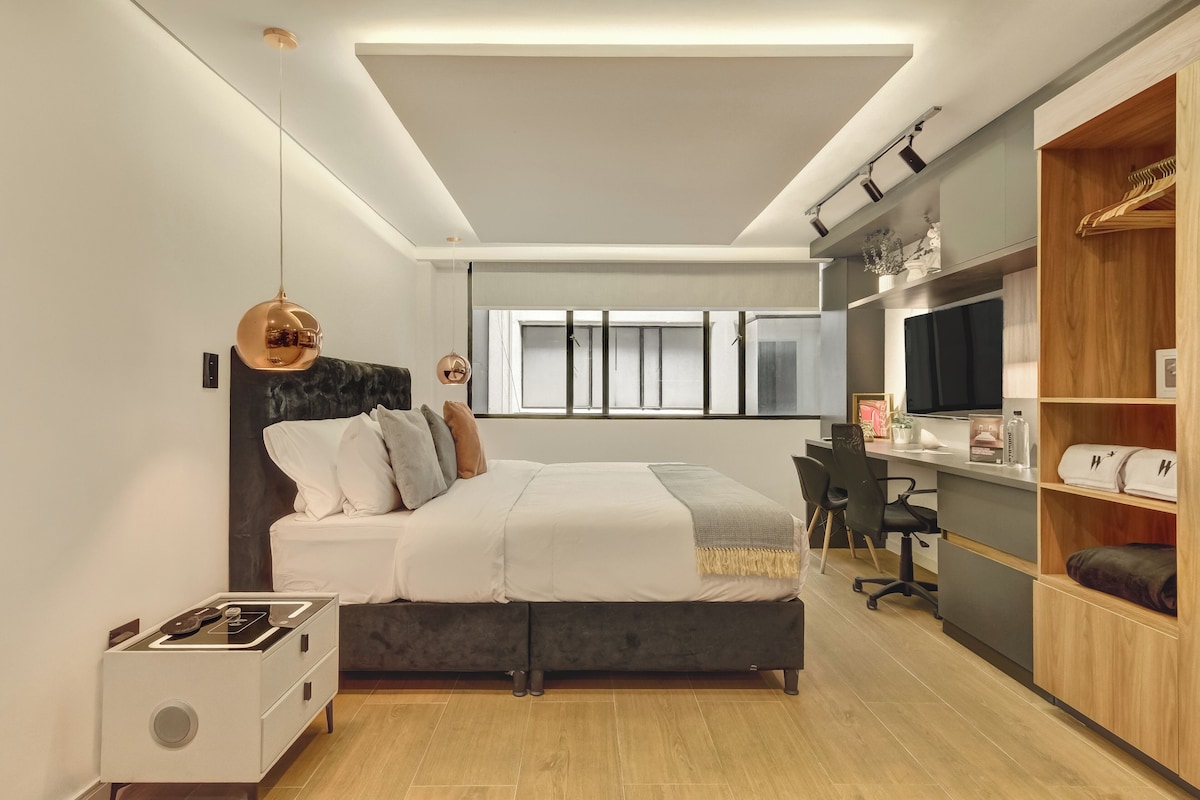 Ein modernes Schlafzimmer mit Bett, Nachttisch, Fernseher und integriertem Kleiderschrank.