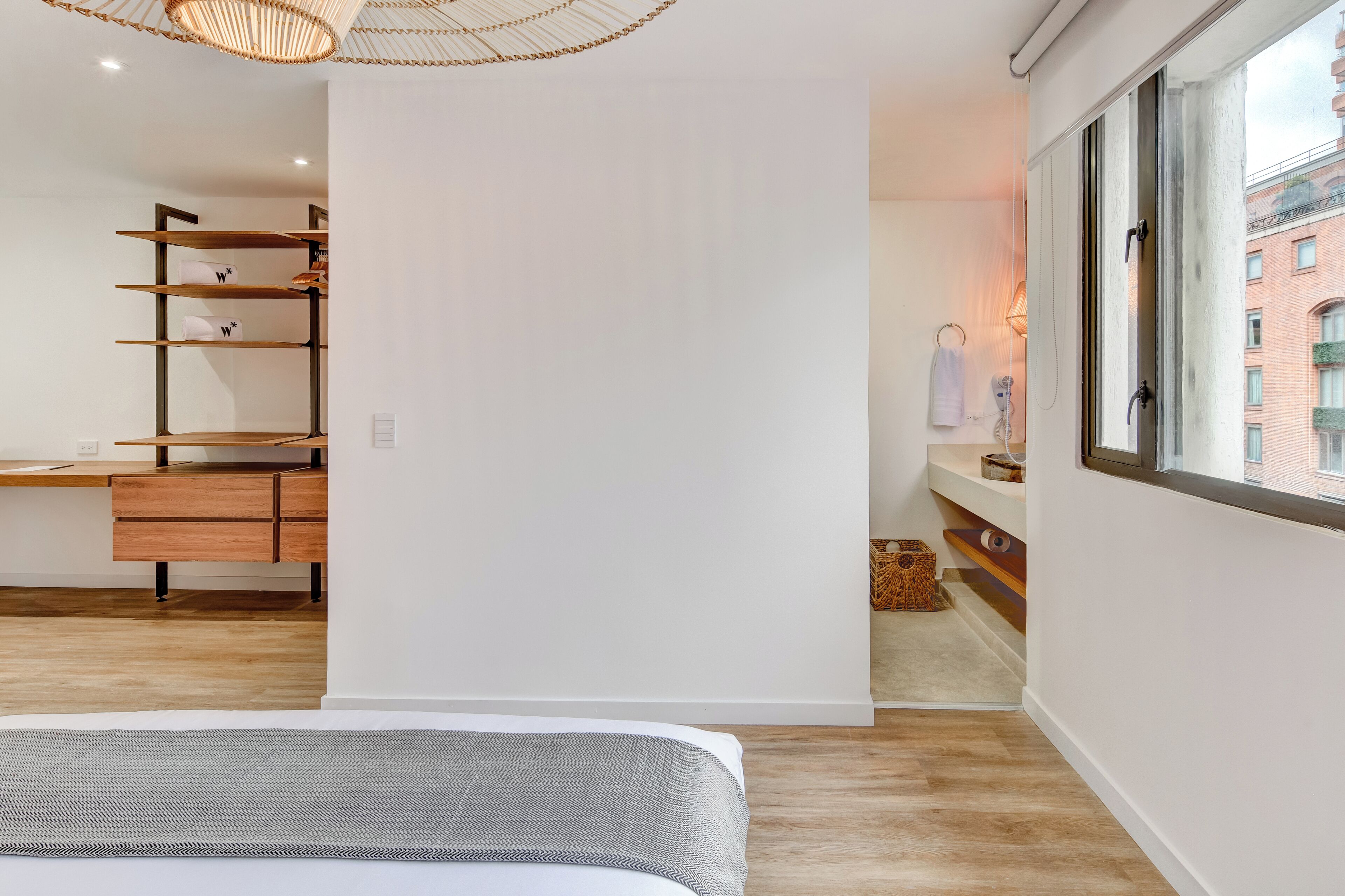 A modern bedroom with a bed, wooden desk, and built-in shelving.