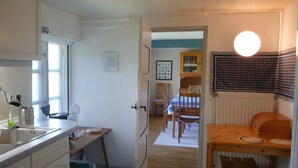 Una cocina con lavamanos, armarios y un comedor con mesa y sillas.