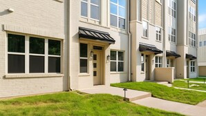 Un edificio residencial de varios pisos con fachada uniforme, ventanas amplias y un césped bien cuidado.