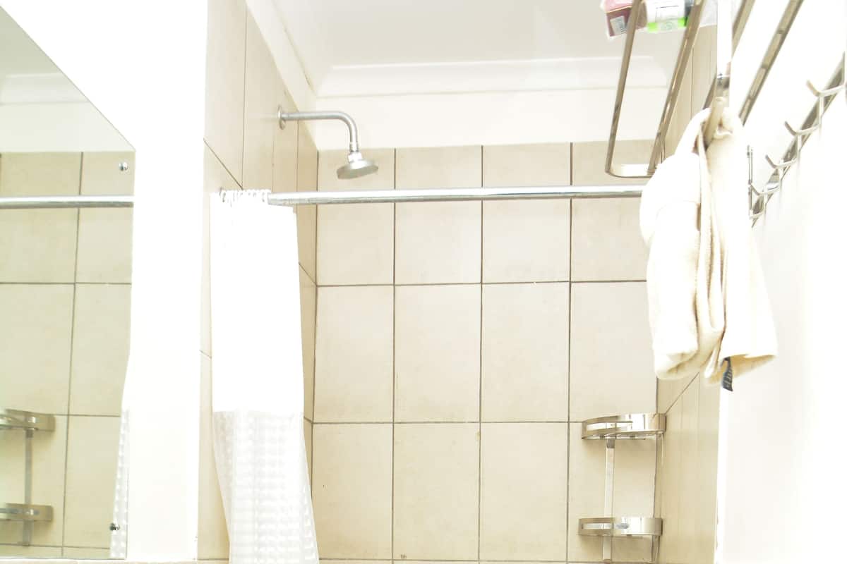 A bathroom with a shower, a sink, and a towel rack.