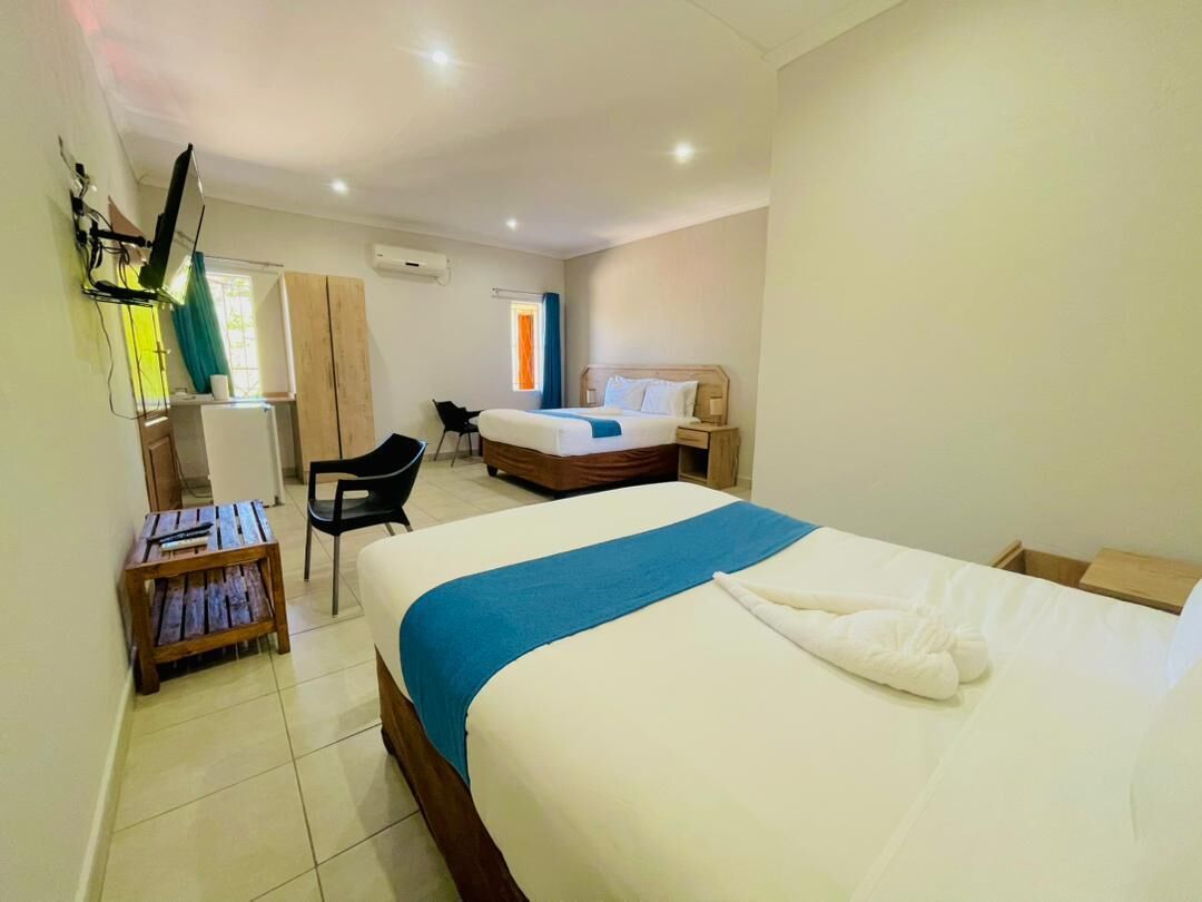 A hotel room with a bed, a desk, a chair, and a small table.