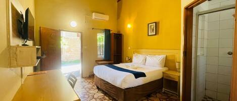 Una habitación con cama, mesa, televisor y ducha.