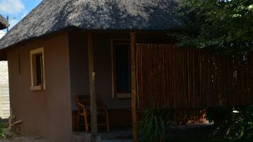 A house with a thatched roof, a porch with a chair, and a wooden fence.