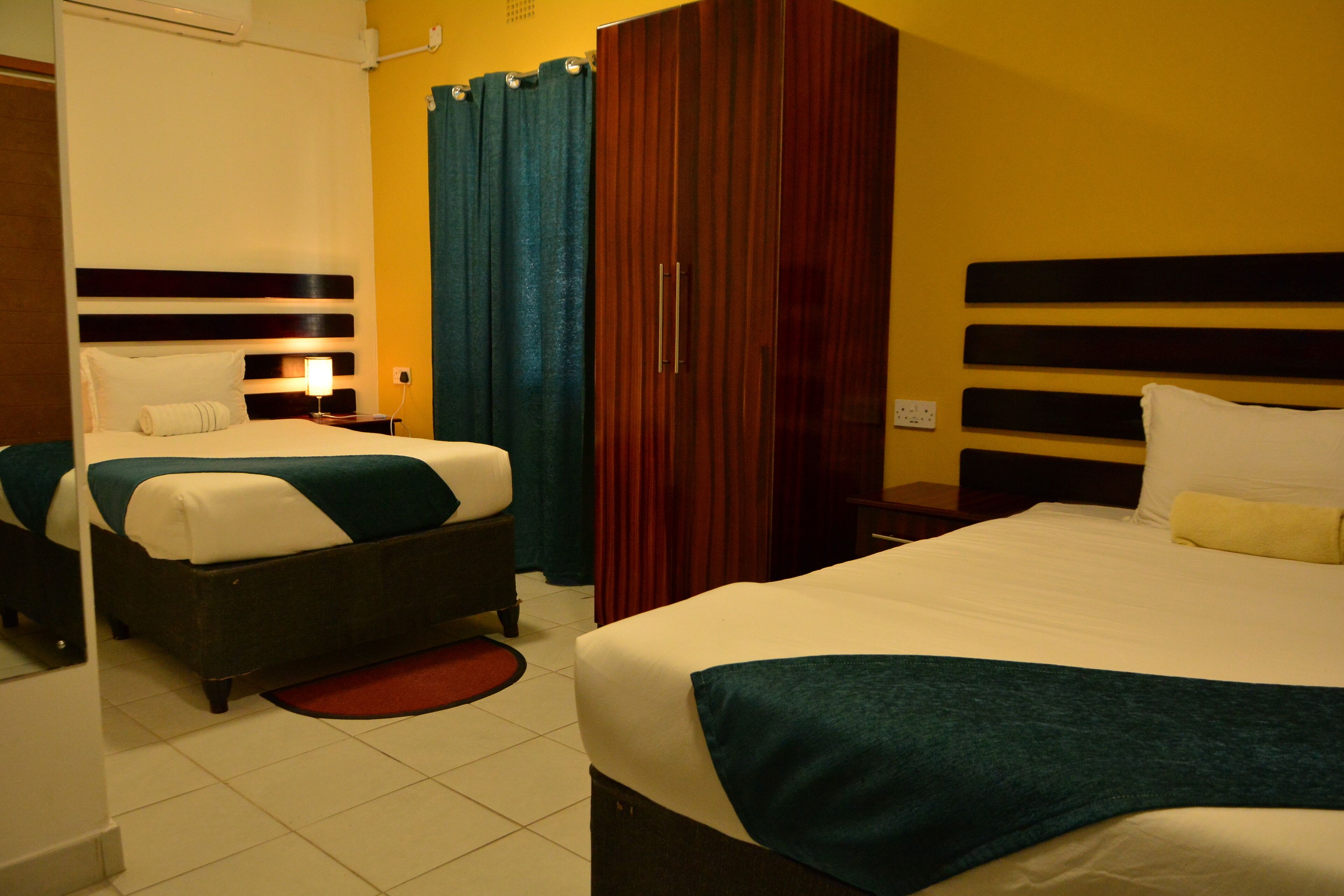 Une chambre d’hôtel avec deux lits, une armoire et une salle de bain.