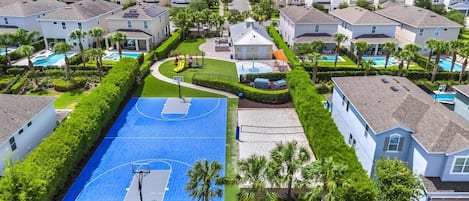 An aerial view of a residential area with houses, a basketball court, and a swimming pool.