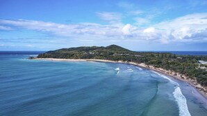A coastal landscape with a beach, clear blue waters, and a hill with vegetation. - Byron Bay Accom - Forty Five on Lawson Apt 7 (Byron Bay)