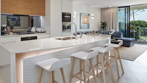 A modern kitchen with a large island, bar stools, and a dining area with a view. - Byron Bay Accom - Forty Five on Lawson Apt 7 (Byron Bay)