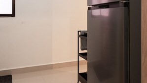 A modern kitchen with a black refrigerator, a small shelf unit, and a tiled floor. - Cozy Studio in Gazcue, Steps to Zona Colonial (Santo Domingo)