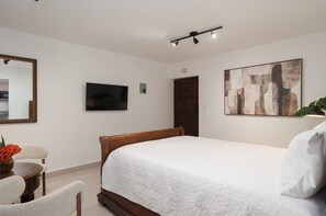 Een slaapkamer met een bed, een televisie, een schilderij en een deur.
