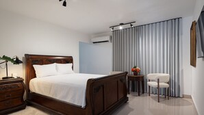 A neatly arranged bedroom with a wooden bed, a bedside table, a chair, and a small table with a vase. - Cozy Studio in Gazcue, Steps to Zona Colonial (Santo Domingo)