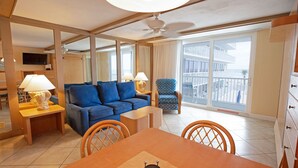 A hotel room with a dining area, a sofa, a chair, a TV, and a balcony with a view. - 1BR Oceanfront Condo w/ Full Kitchen & Balcony (Daytona Beach Shores)
