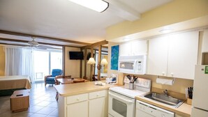 Habitación de hotel compacta con kitchenette, una cama, un pequeño comedor y un baño.