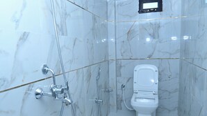 A modern bathroom with a toilet, shower, and glass-enclosed shower stall. - White stay house  (Azamgarh)