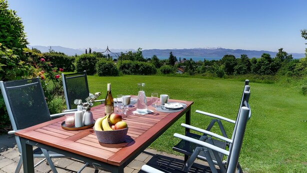Een houten tafel buiten, met uitzicht op bergen en een meer.