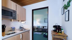 Een moderne keuken met een magnetron, spoelbak en houten kastjes.
