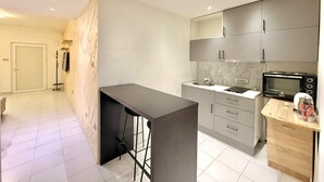 A modern kitchen with grey cabinets, a microwave, and a bar stool. - Adriatic Central 2BDR Apartment (Budva)