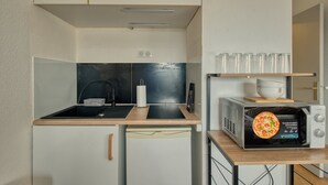 Une cuisine compacte équipée d’un évier, d’un four à micro-ondes et d’un petit réfrigérateur.