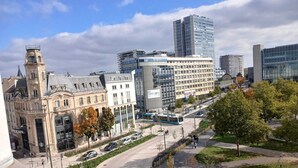 Une rue de la ville bordée de bâtiments historiques, d’une architecture moderne et où circule un autobus.