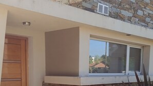 A modern house with a stone facade, a wooden door, and a tiled patio. - Sea house (Miramar)