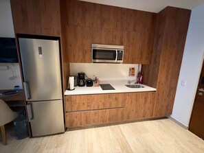 A compact kitchen with a built-in microwave, a stainless steel refrigerator, and a sink. - Centro Playa Del Carmen Duna  206 (Playa del Carmen)