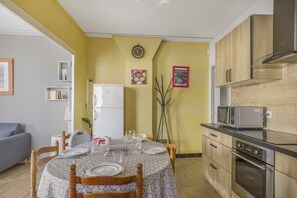 Kompakti keittiö, jossa on ruokailutila, jääkaappi, mikroaaltouuni ja liesi.