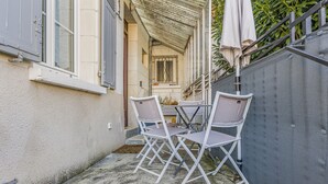 Een terras met een tafel en stoelen, een overdekt gedeelte, en uitzicht op een straat.