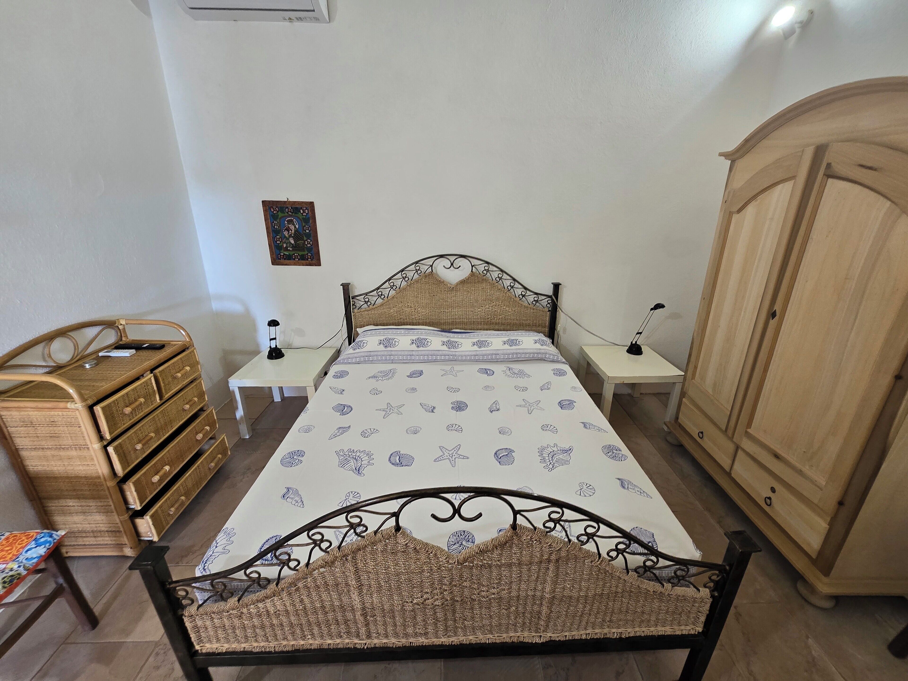 Quarto com cama, mesas de cabeceira, guarda-roupa e cômoda.