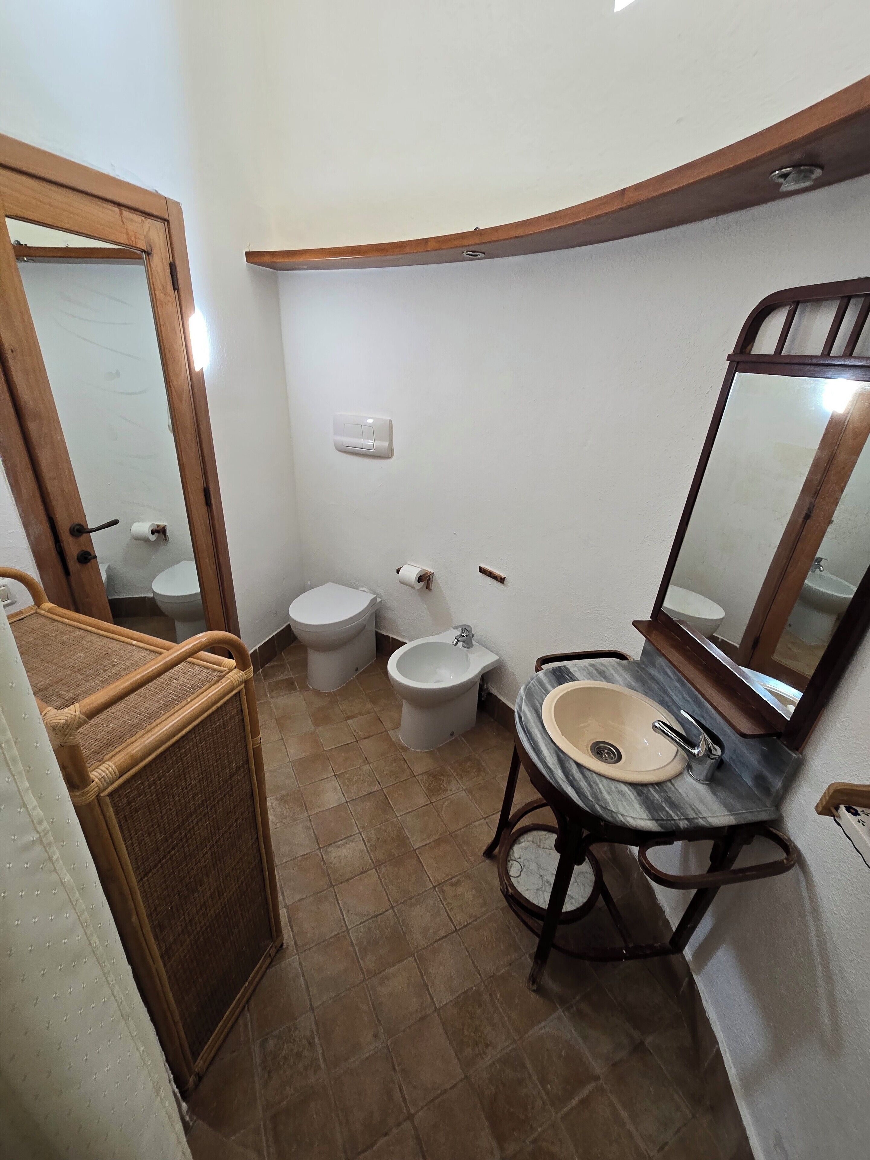 A compact bathroom with a toilet, bidet, and sink.