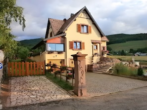 Ein zweistöckiges Haus mit einer Steintreppe, einem Holzzaun und einem gepflasterten Zugang.