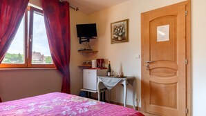 Un dormitorio con cama, escritorio, televisor y una puerta.
