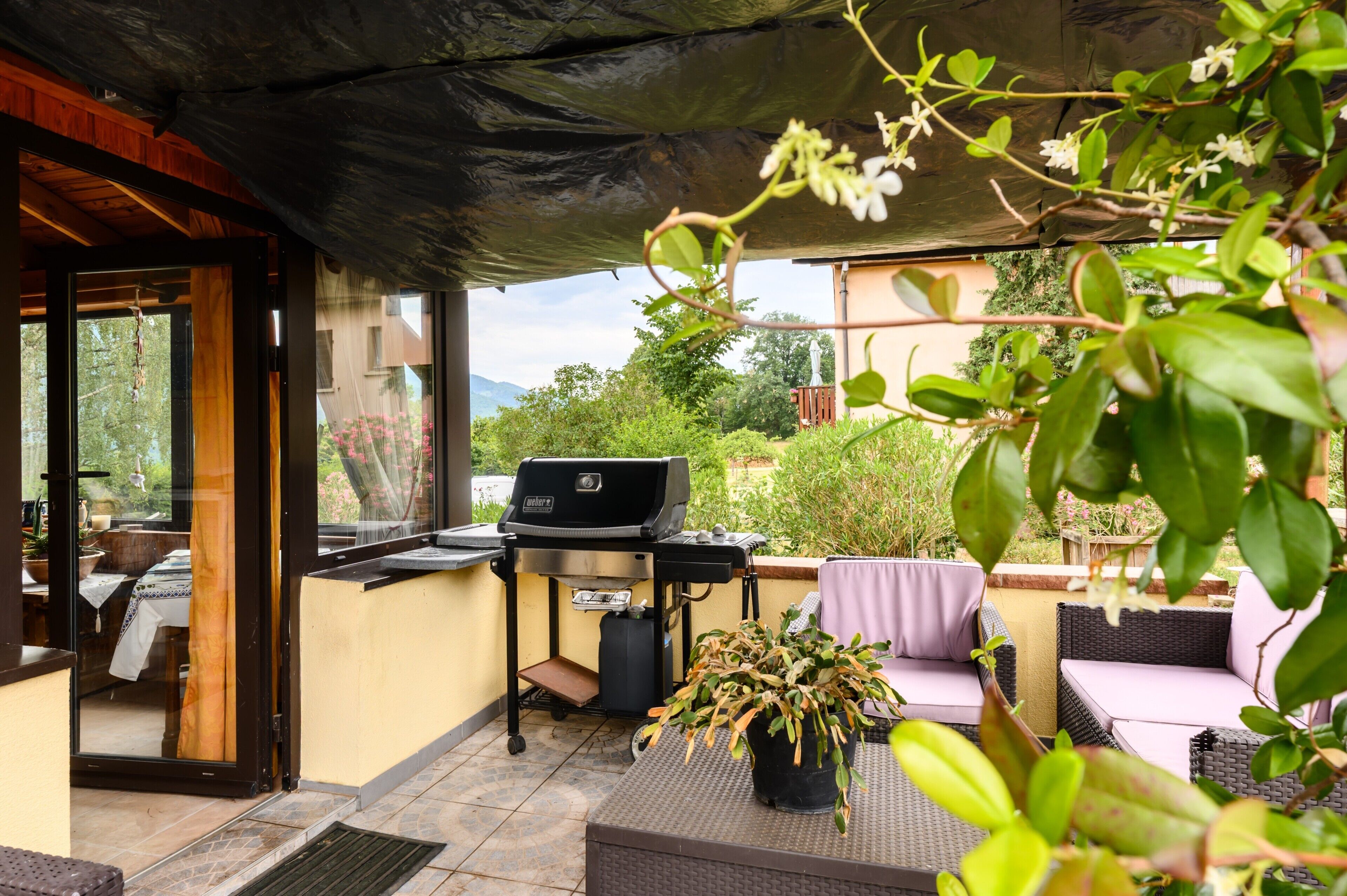 An outdoor patio with a grill, seating, and a view of the surrounding landscape.
