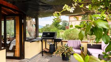 An outdoor patio with a grill, seating, and a view of the surrounding landscape.