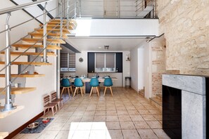 A modern kitchen with a dining area, a staircase, and a fireplace. - Holiday Home 'Gîte Le Rabelais' with Private Pool, Private Terrace and Wi-Fi (Thésée)