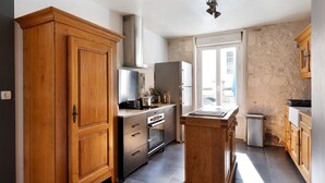 A kitchen with wooden cabinets, stainless steel appliances, and a stone wall. - Holiday Home 'Gîte Le Rabelais' with Private Pool, Private Terrace and Wi-Fi (Thésée)