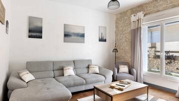 En moderne stue med en grå modulsofa, et træbord og kunst på væggene.