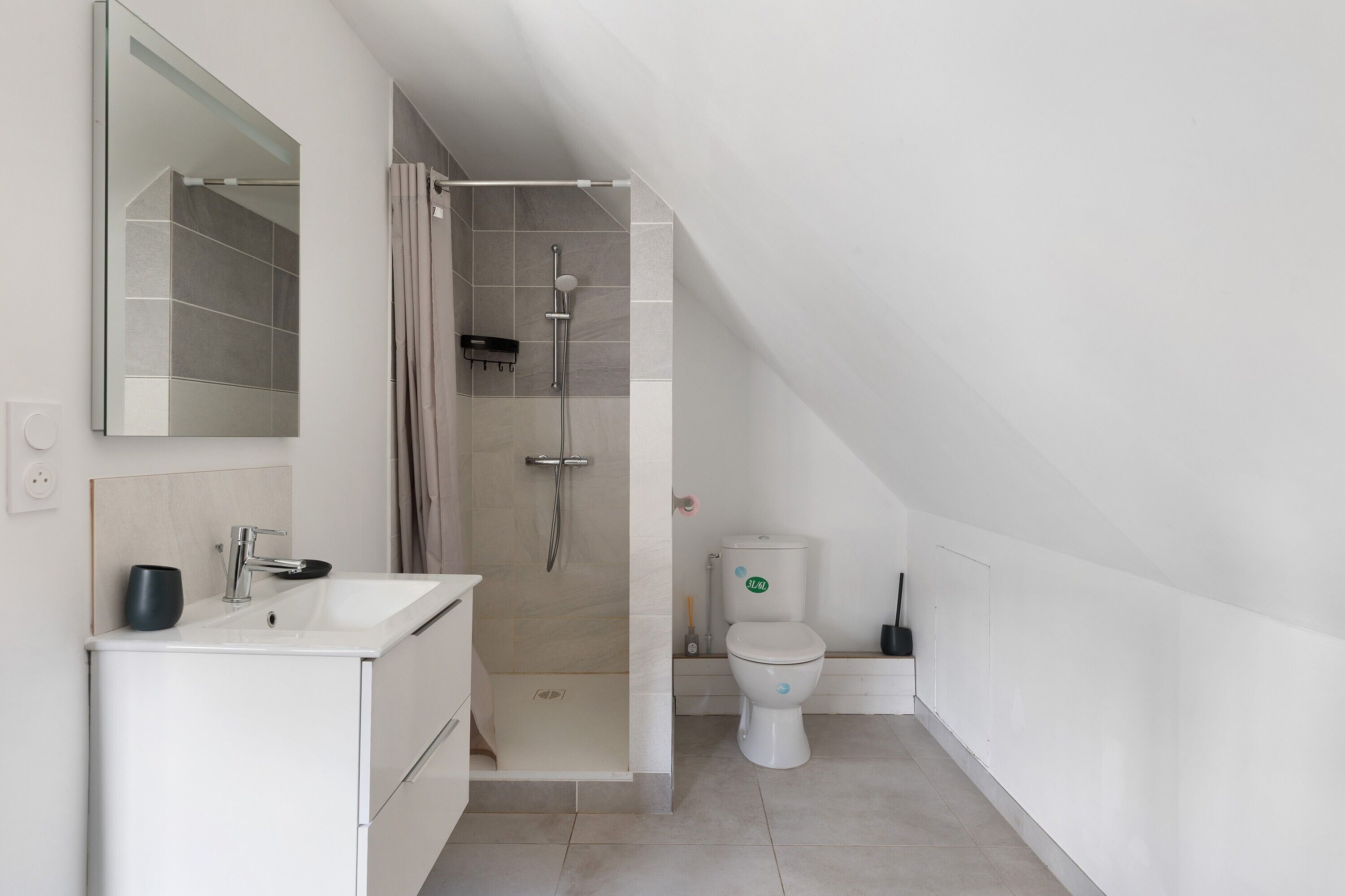 A modern bathroom with a shower, toilet, and sink.