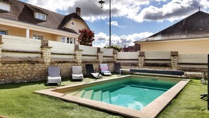 A swimming pool with a stone wall, a covered bench, and lounge chairs. - Holiday Home 'Gîte Le Rabelais' with Private Pool, Private Terrace and Wi-Fi (Thésée)