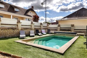 A swimming pool with a stone wall, a covered bench, and lounge chairs. - Holiday Home 'Gîte Le Rabelais' with Private Pool, Private Terrace and Wi-Fi (Thésée)
