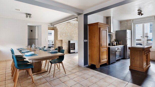 A spacious kitchen with modern appliances, a dining area with chairs, and a view of the outdoors. - Holiday Home 'Gîte Le Rabelais' with Private Pool, Private Terrace and Wi-Fi (Thésée)