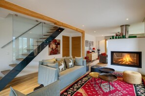 A modern living room with a sofa, a fireplace, and a staircase.
