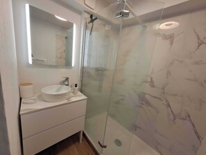 A modern bathroom with a glass shower enclosure, a white vanity with a sink, and a mirror above the vanity. - Bright studio for a relaxing stay in Le Touquet (Le touquet)