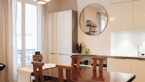 Een moderne keuken met een eettafel, stoelen en een spiegel.