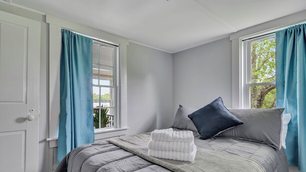 A bedroom with a bed, curtains, and a window. - Cozy Lakehouse with Game Room (Orono)